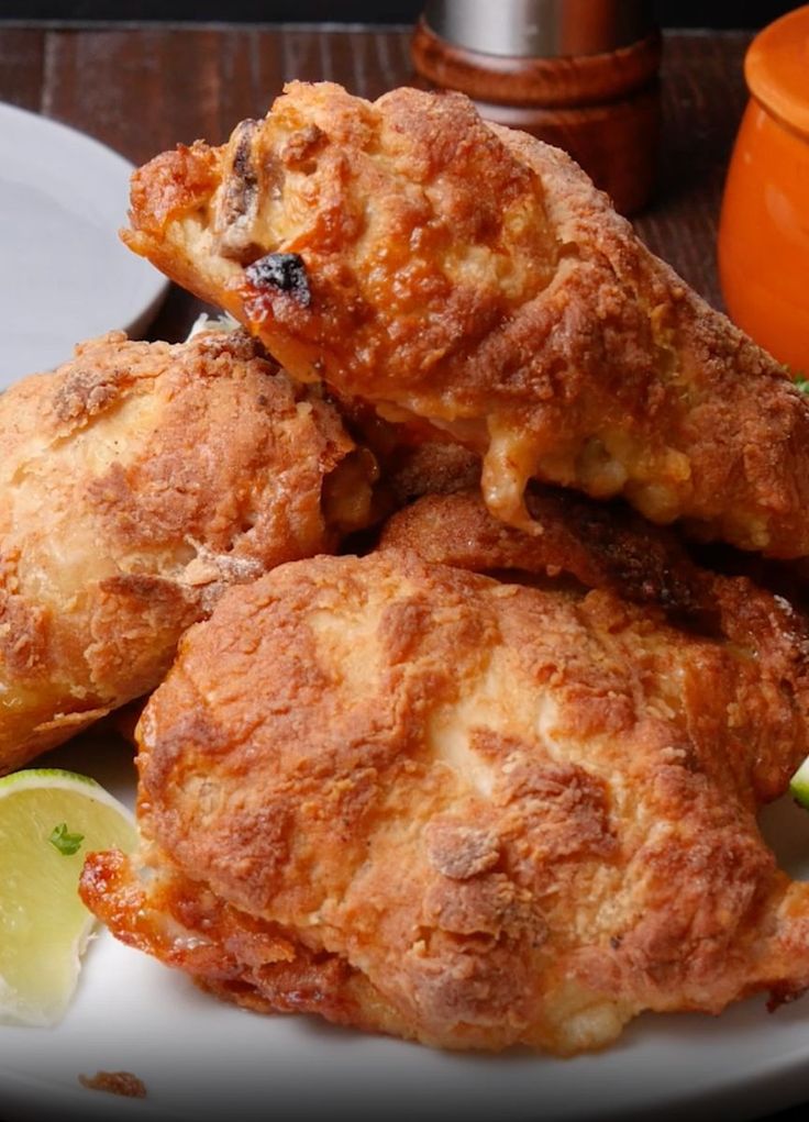 some fried food on a white plate with lemon wedges