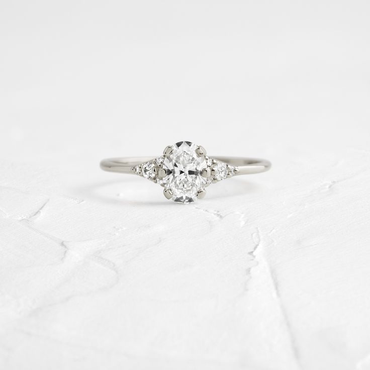 Oval cut focal diamond of your choice. Need help choosing a diamond? Our Customer Care team is right here. Due to its unique setting, Melanie recommends a shorter oval cut over a longer skinny one as it will blend best with the band. This design features a closed basket setting with six prongs on a delicate 1.2mm band—available in platinum or 14k solid yellow, white or rose gold. The band is accented by eight (1-1.8mm) round white diamonds, four on each side of the focal stone. The exact size of Melanie Casey, Basket Setting, Necklace Chain Lengths, Glass Slipper, Diamond Settings, Oval Cut Diamond, The Lady, Customer Care, Gold Set