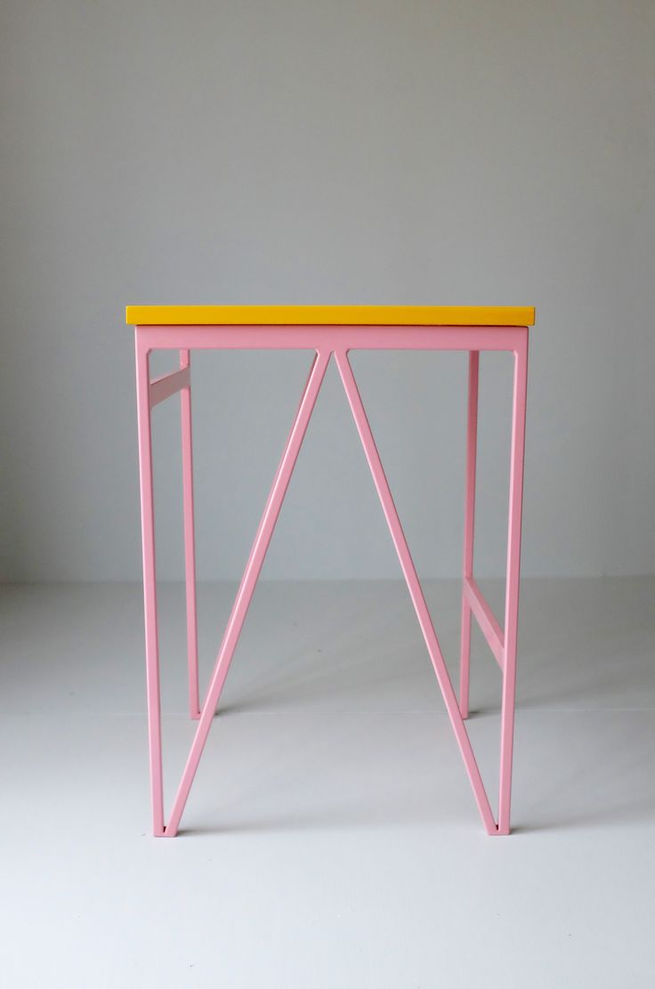 a pink table with yellow top against a gray background, in the shape of a triangle