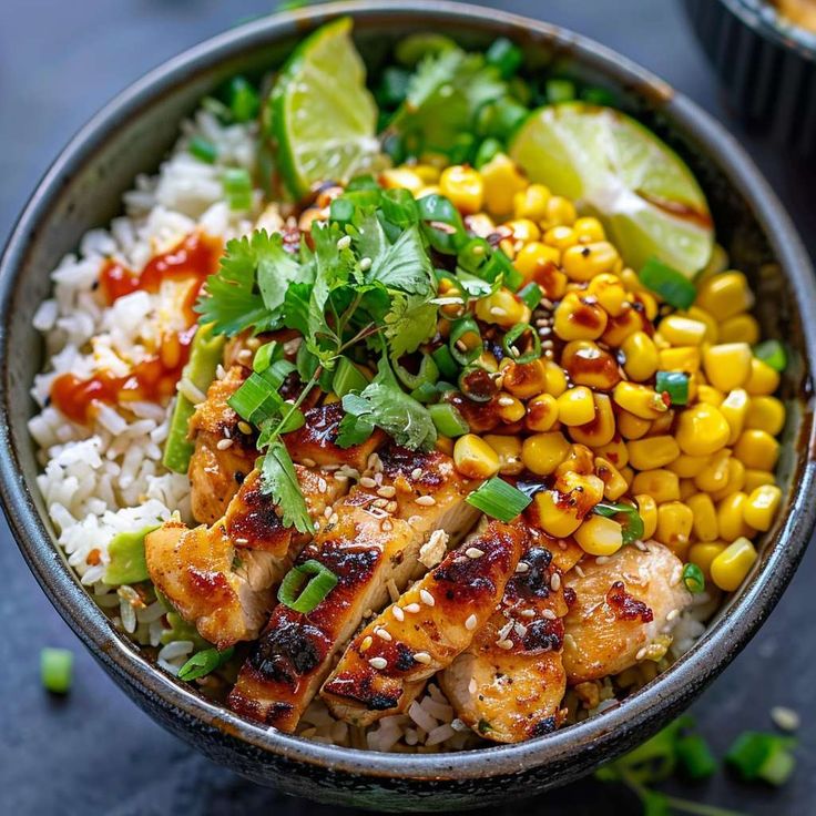 a bowl filled with chicken, rice and corn on top of a blue table cloth