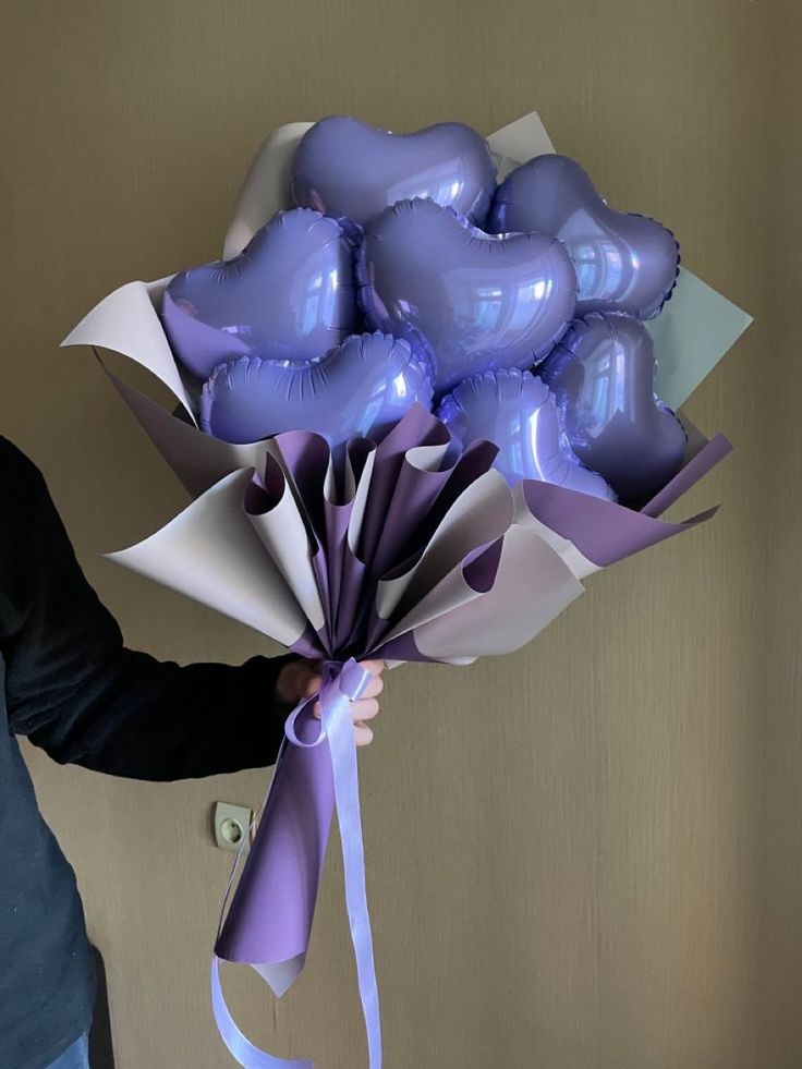 a man holding a bunch of purple heart shaped balloons