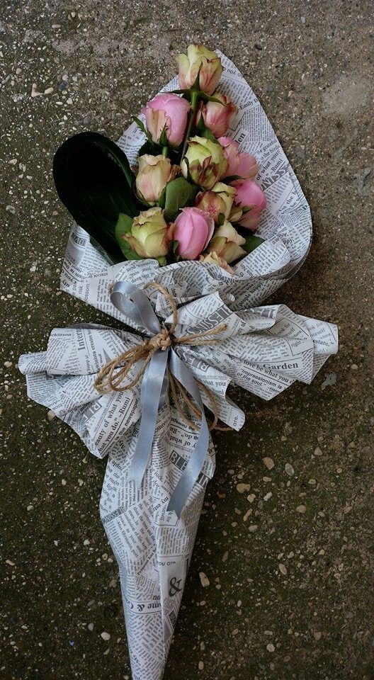 a bouquet of flowers wrapped in newspaper on the ground