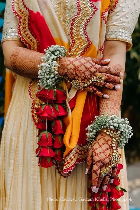 a woman in a white and red outfit holding flowers on her arm with both hands