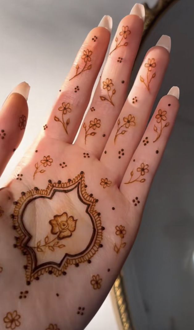 a woman's hand with henna tattoos on it and flowers all over the palm