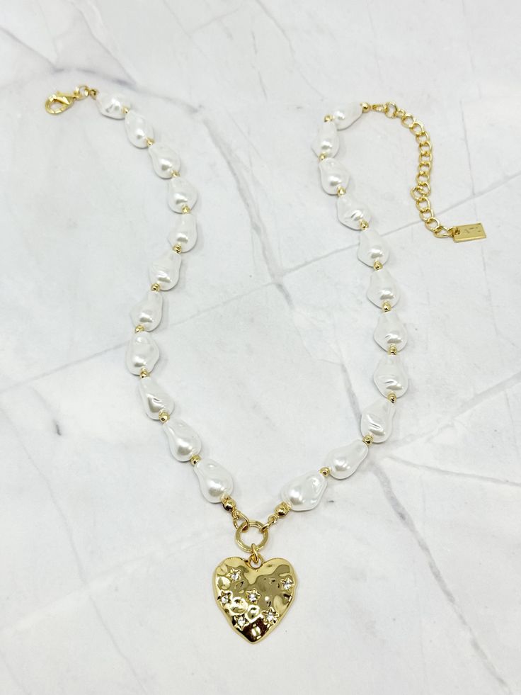 Fall in love with this Still Standing Pearl Heart Necklace! This gold heart necklace is adorned with delicate acrylic pearl strands, making it the perfect accessory for any outfit. Stay stylish and stand out from the crowd with this unique piece. Imitation Pearl Beads 48 cm long 18k Gold Plated Over Brass Extendable Lobster Clasp Dainty Necklace With Pearl Charm, Heart-shaped Pearl Beaded Chain Jewelry, Heart-shaped Pearl Chain Necklace For Parties, Heart Shaped Pearl Charm Necklace For Party, Heart-shaped Pearl Charm Necklace For Party, Gold Heart Necklaces With Pearl Charm, Gold Pearl Necklace With Heart Pendant And Beads, Pearl Necklace With Heart Charm For Parties, White Pearl Heart Necklace With Pearl Charm