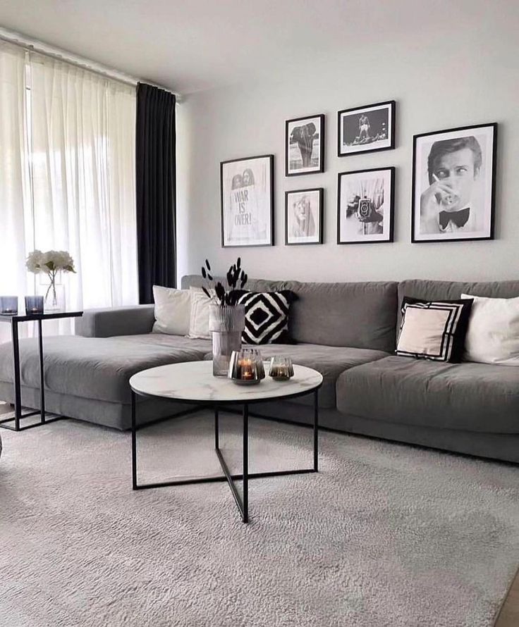 a living room with gray couches and pictures on the wall above them, along with coffee table