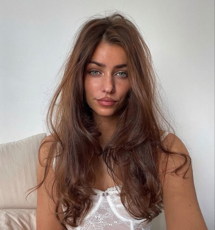 a woman sitting on a couch with her hair blowing in the wind and looking at the camera