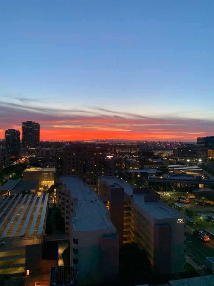 the sun is setting over an urban area with tall buildings and skyscrapers in the background