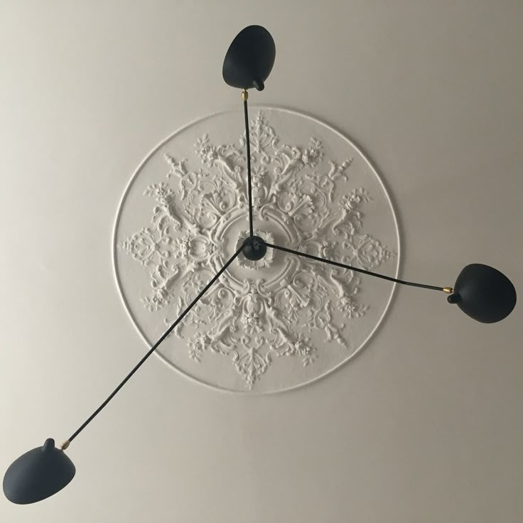 a clock that is on the wall with three lights hanging from it's sides