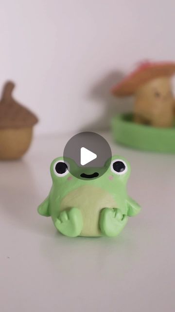 a green frog toy sitting on top of a white table next to other small toys