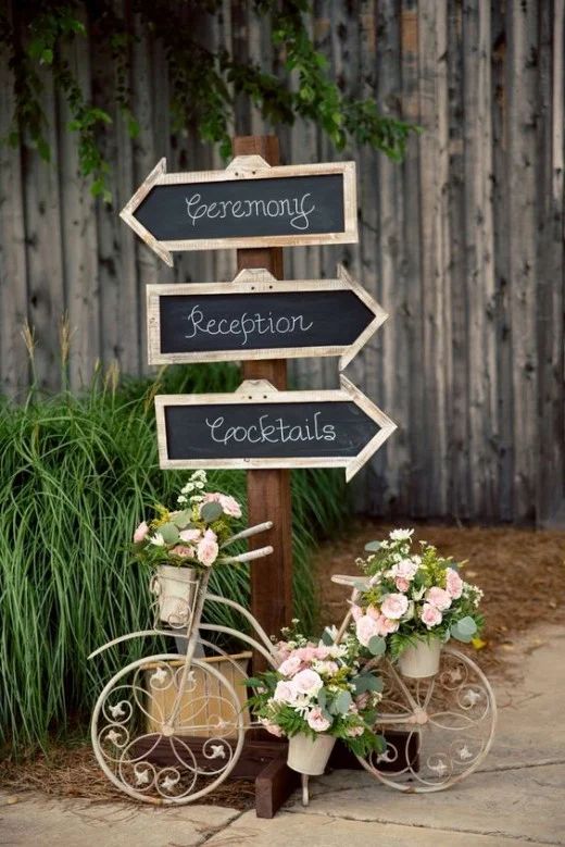 a bicycle is parked next to a sign that says reception, cocktails and flowers