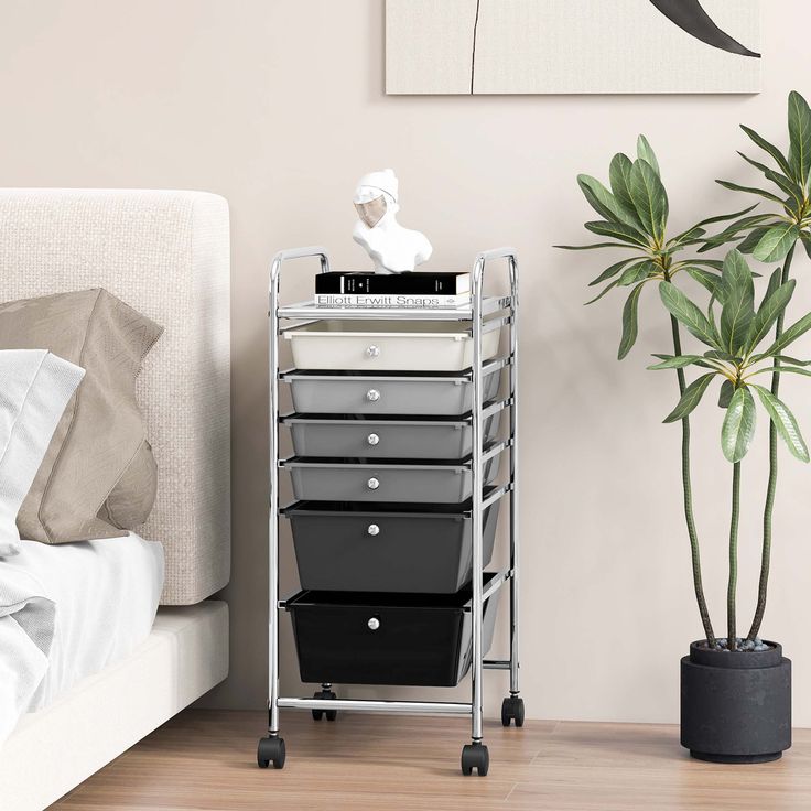 a metal cart with five drawers next to a potted plant