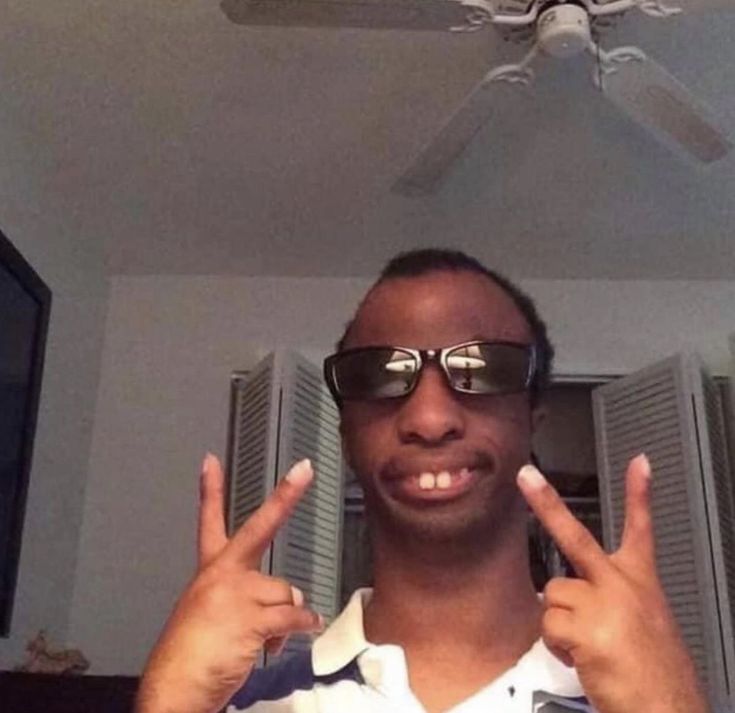 a man wearing sunglasses is making the peace sign with his fingers in front of him