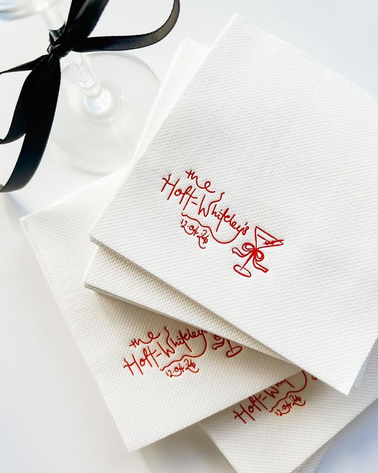 three napkins with happy birthday written on them next to a wine glass and black ribbon