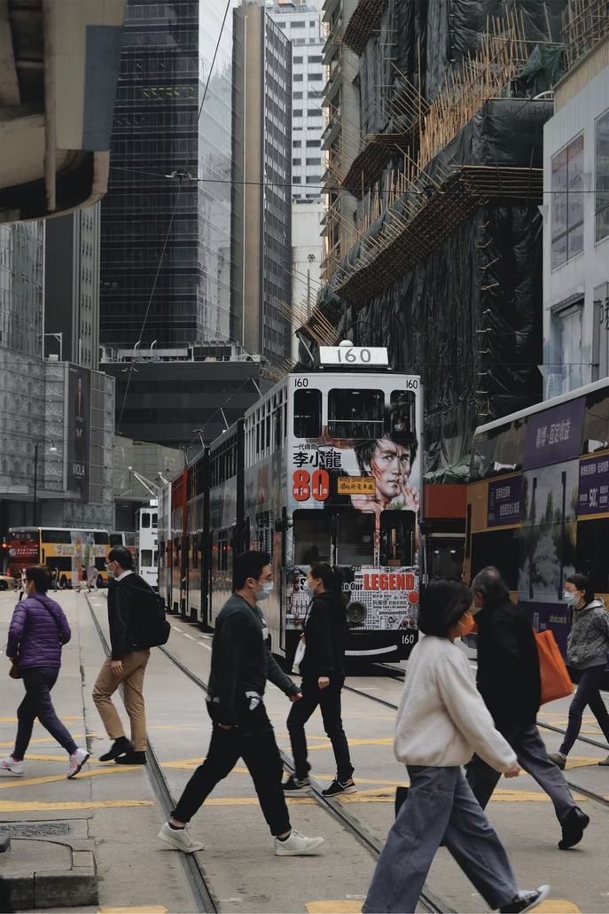 people crossing the street in front of a double decker bus on a busy city street