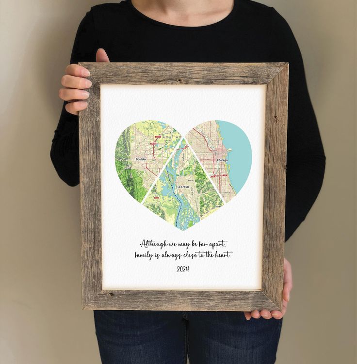 a woman holding up a framed map with two hearts in the shape of a heart