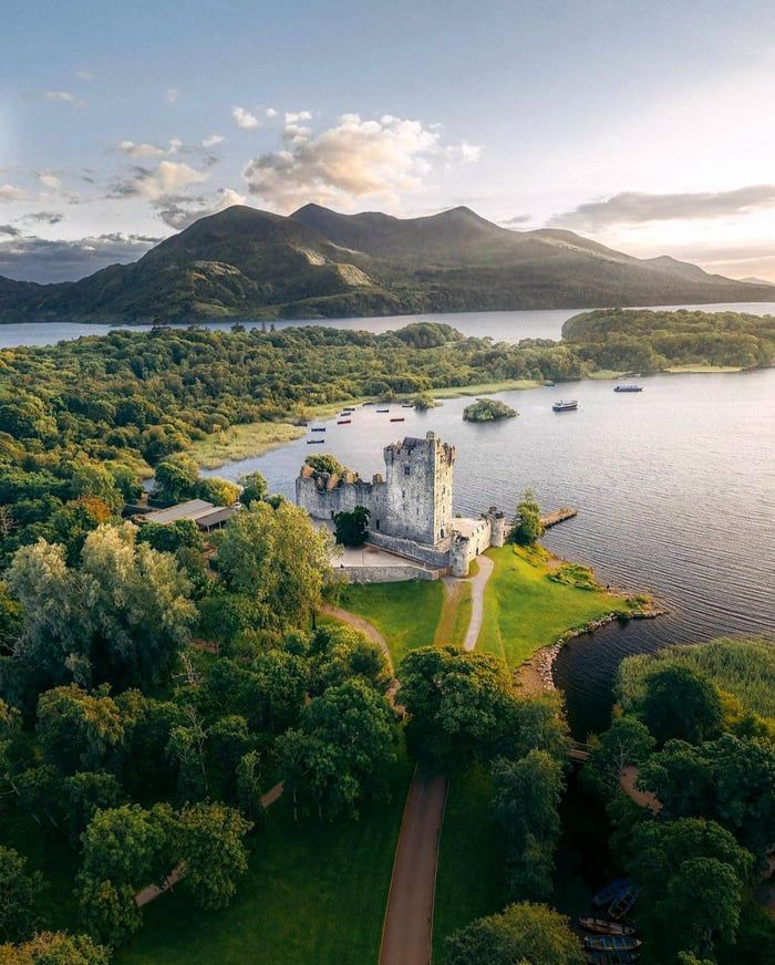 an aerial view of a castle in the middle of a lake surrounded by green trees