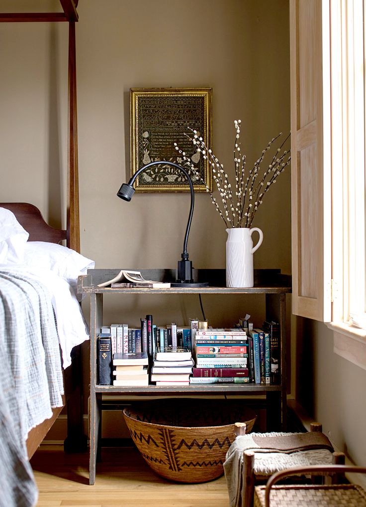 a bed room with a neatly made bed and a book shelf filled with books next to a window