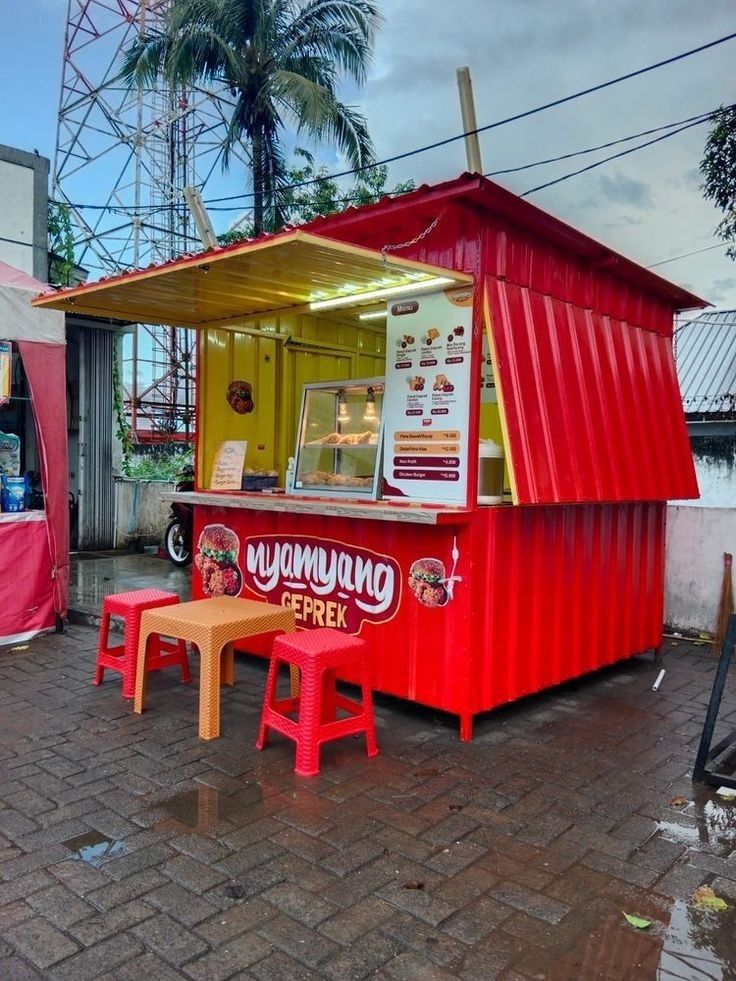 a red food cart sitting on top of a brick sidewalk