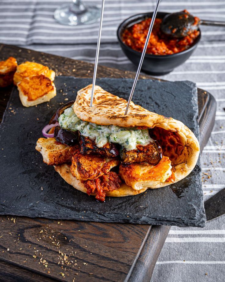 a sandwich with meat and vegetables on a slate platter