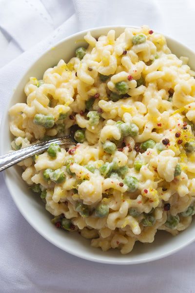 a white bowl filled with macaroni and cheese on top of a white cloth