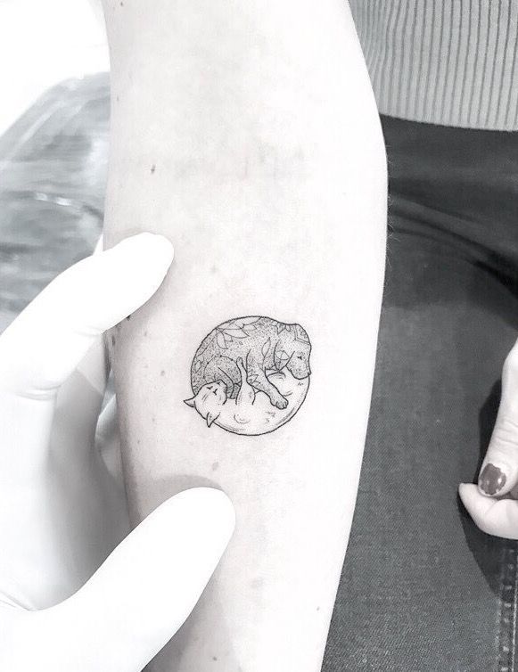 a small cat tattoo on the left inner arm