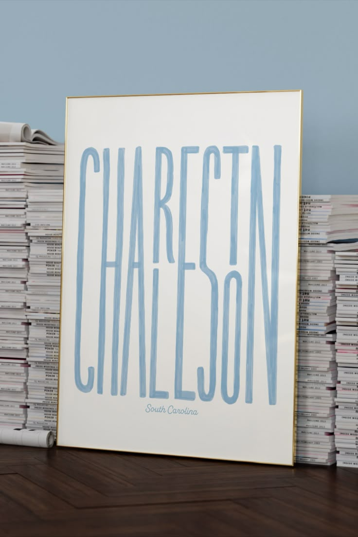 a stack of records sitting on top of a wooden table next to a framed poster