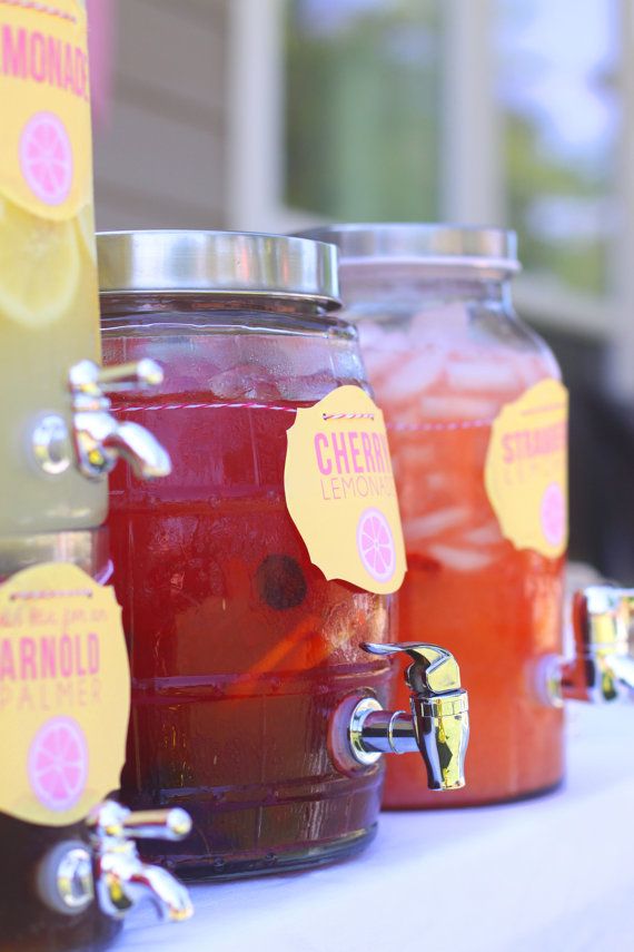 three jars filled with liquid sitting on top of a white table covered in lemonade