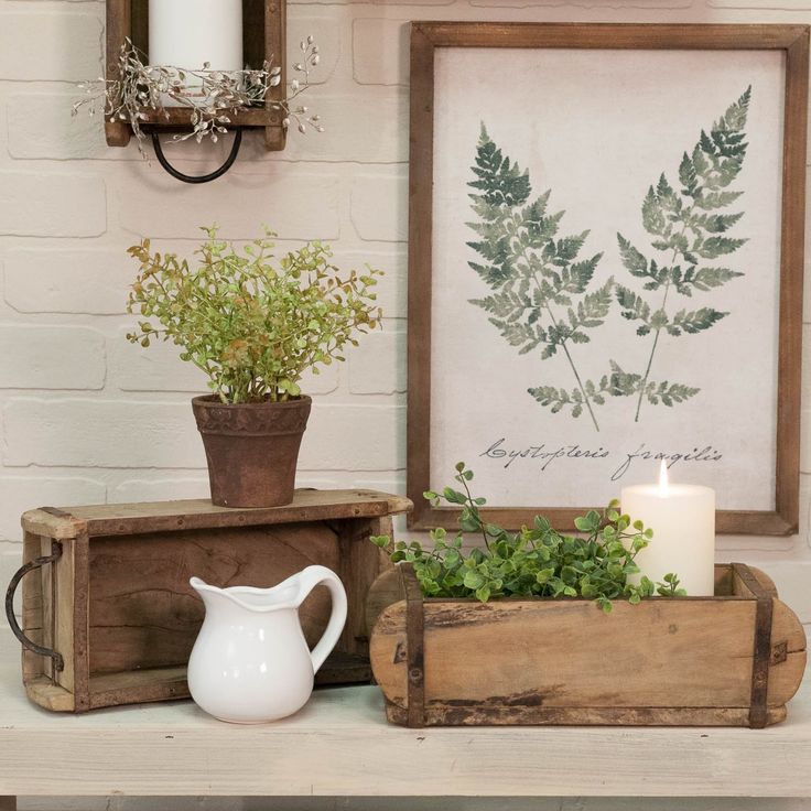 a table topped with two wooden trays filled with plants and a white vase sitting on top of it