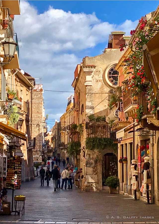 people are walking down the street in an old town