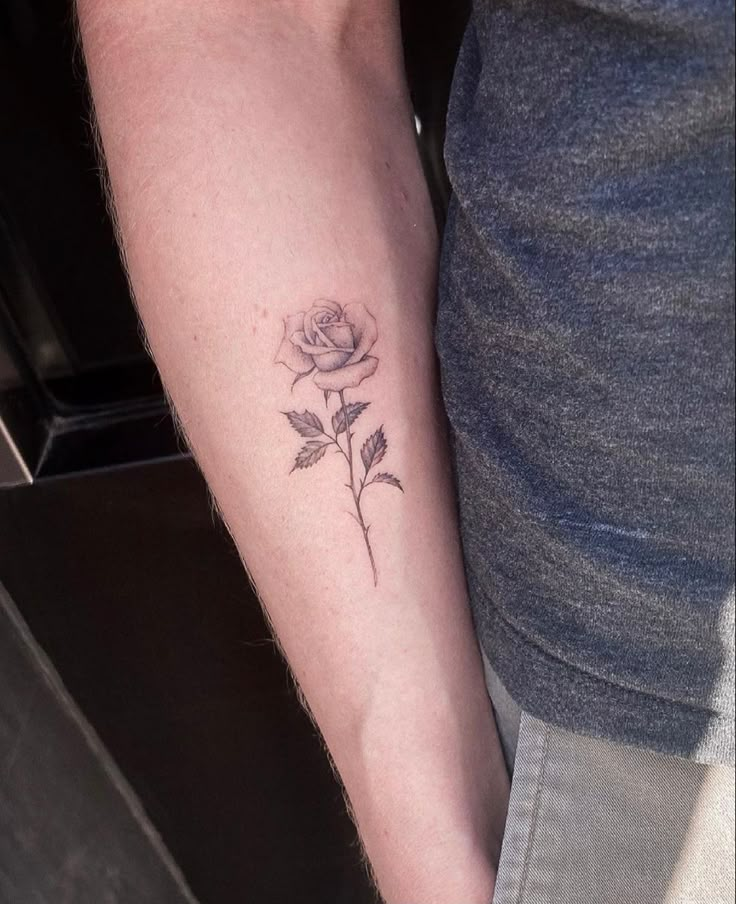 a person with a rose tattoo on their left arm and the other arm behind them