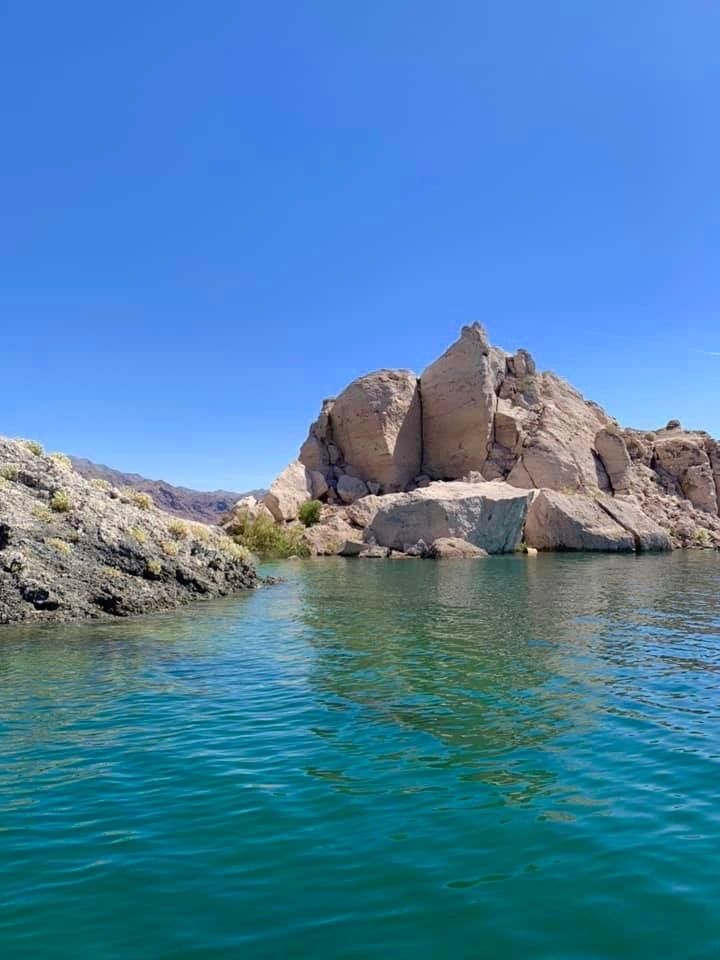 the water is crystal blue and there are rocks in the background