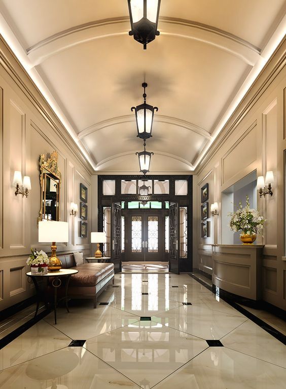 an elegant hallway with white marble floors and large chandeliers on either side of the doors