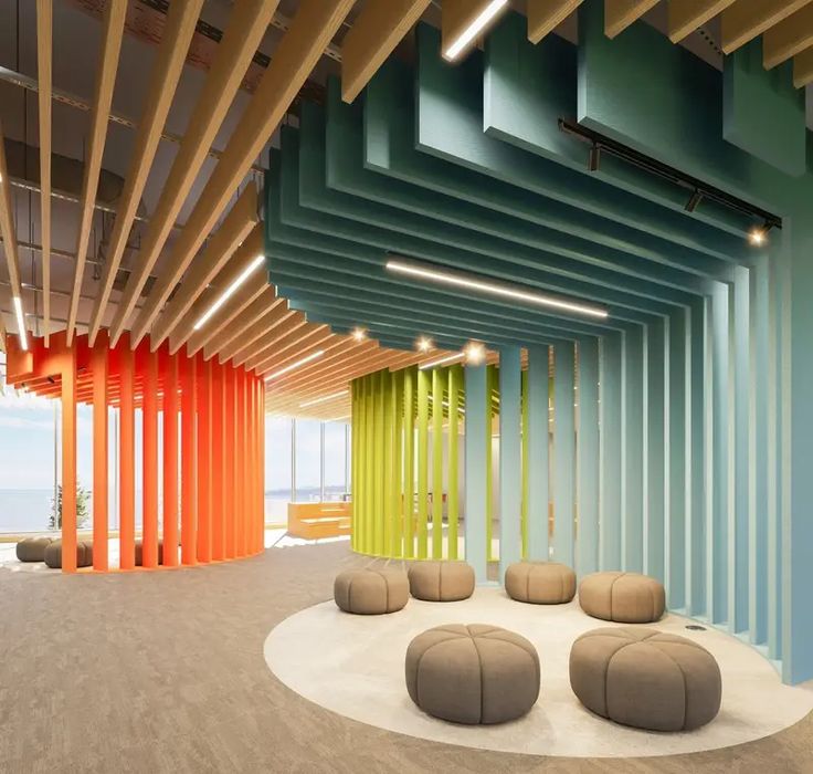 the interior of an office building with colorful columns and round seating on concrete flooring