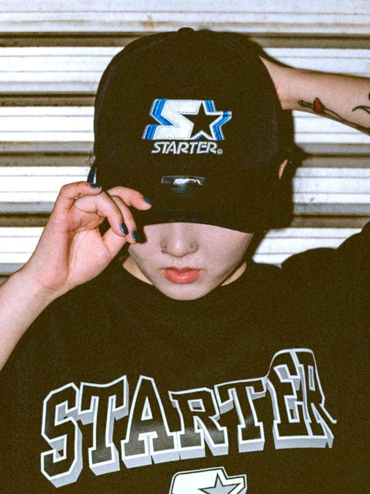 a young man wearing a black hat and holding his hand up to his ear with the word starter on it