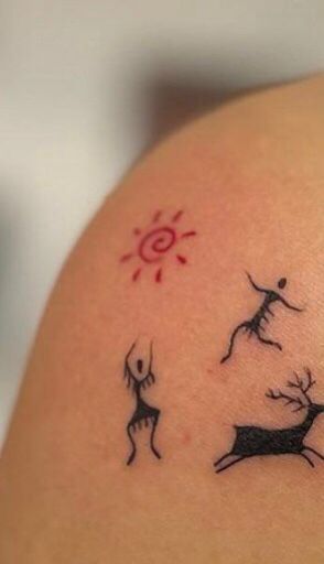 a woman's arm with tattoos on it, including deers and sun in the background