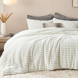 a bed with white comforter and pillows in a bedroom