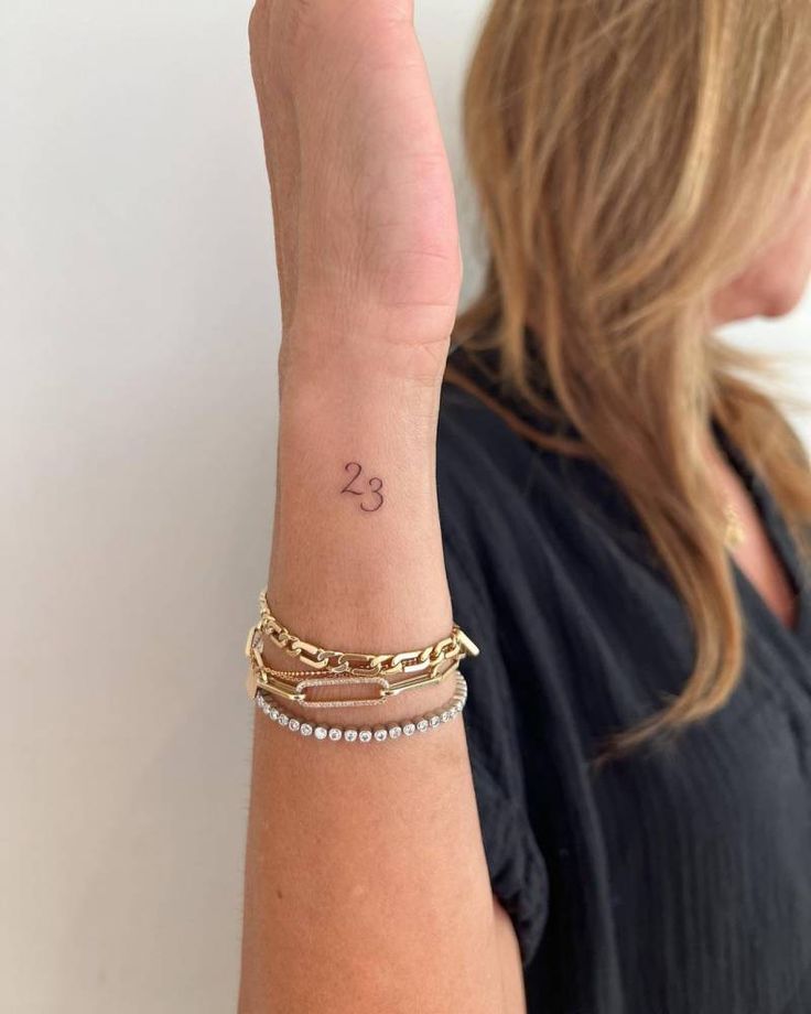 a woman with a tattoo on her arm holding up the number twenty two bracelets