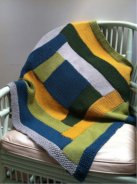 a crocheted blanket sitting on top of a chair next to a white wall