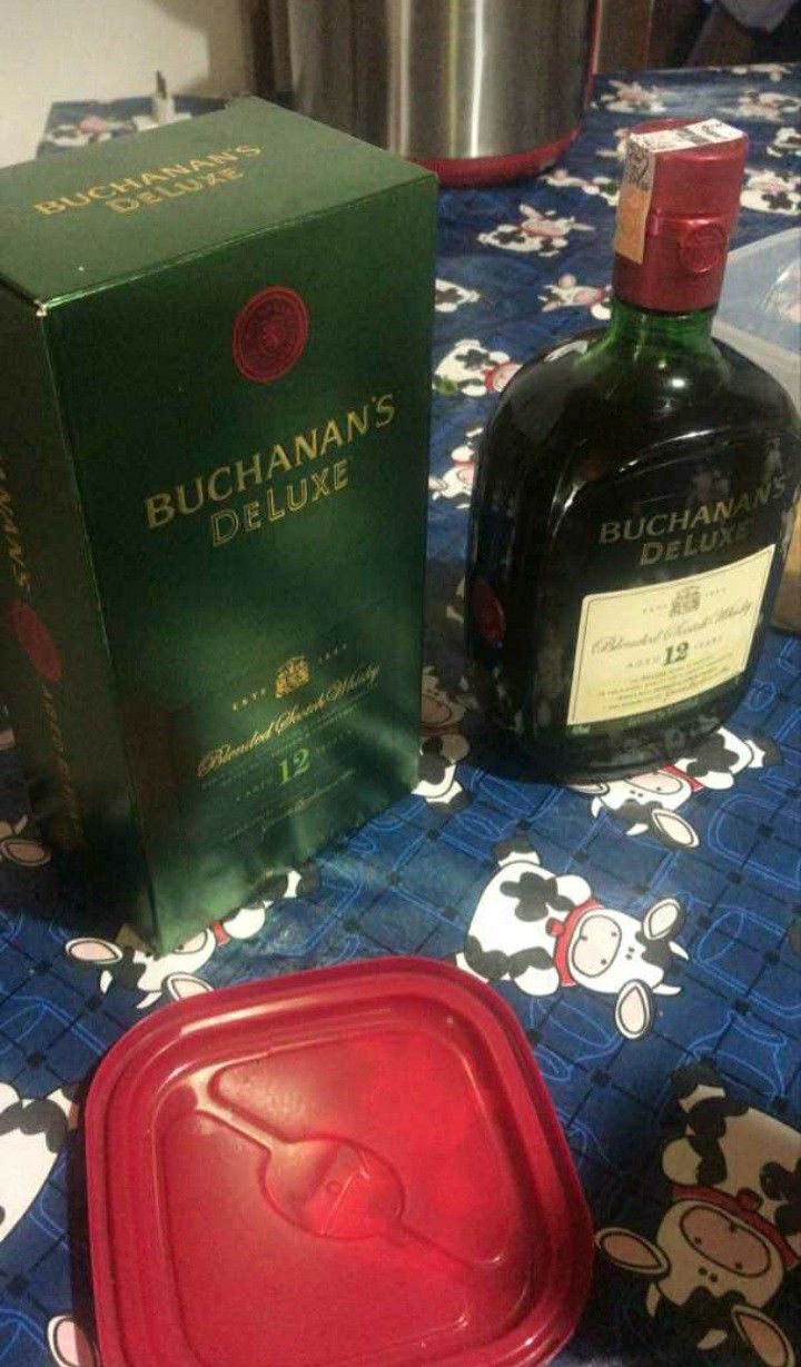 a bottle of buchanna's deluxe and a box of liquor on a table