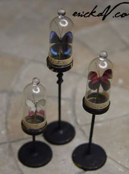 three glass vases with butterflies in them sitting on top of each other near a tile floor