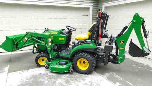 a green tractor parked in front of a garage