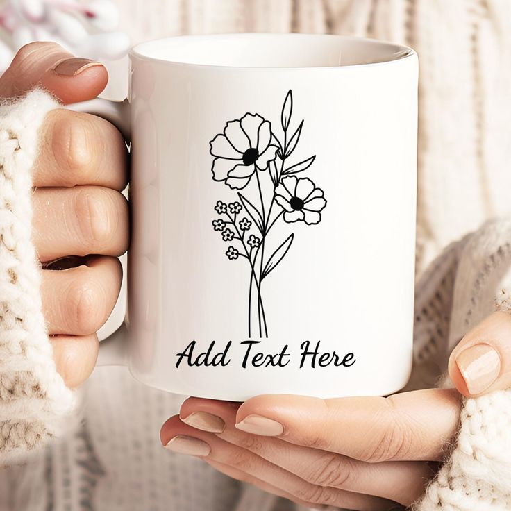 a woman holding a white coffee mug with flowers on the front and side, in her hands