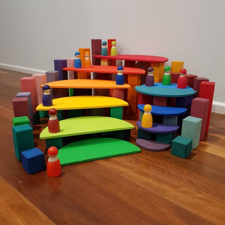 an assortment of colorful wooden toys sitting on the floor in front of a white wall