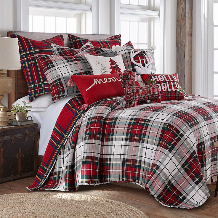 a bed with red and white plaid comforter, pillows and christmas decorations on it