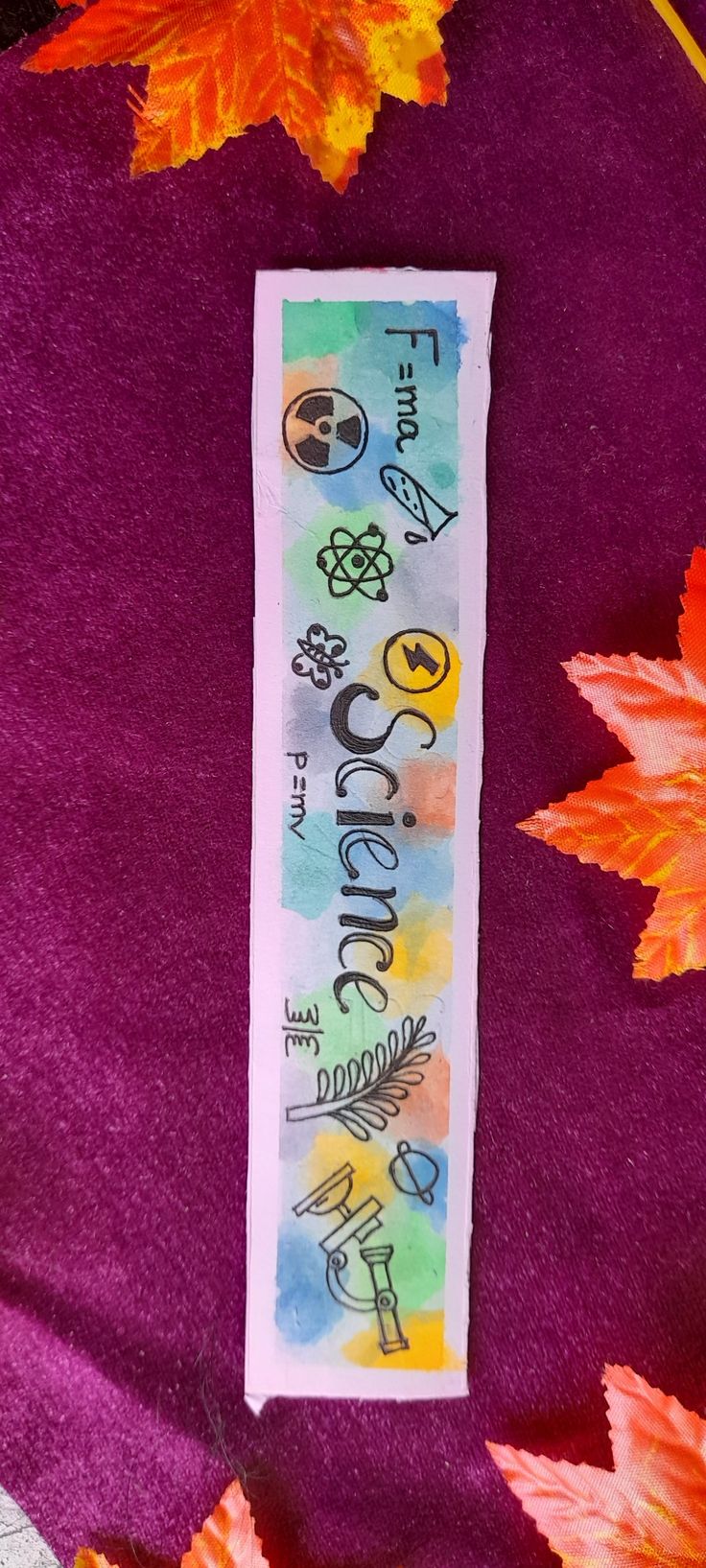 a bookmark with the words science on it surrounded by autumn leaves and acrylic paint