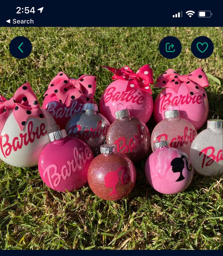 pink and silver baubles with bows on them are sitting in the grass next to each other