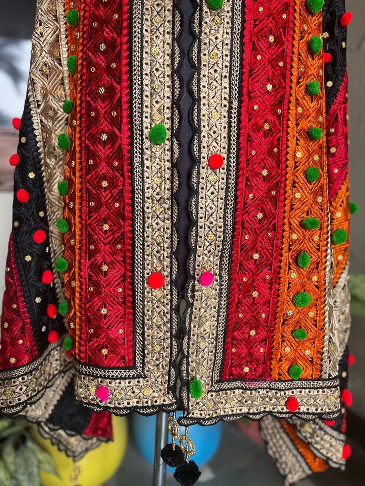 a red and black jacket with pom poms hanging from it's sides