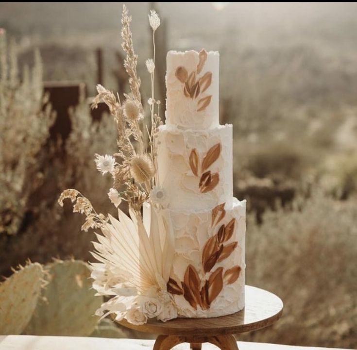 a three tiered cake sitting on top of a wooden table next to a cactus