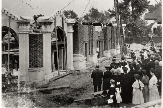 an old black and white photo of people standing in front of a building that is being demolished